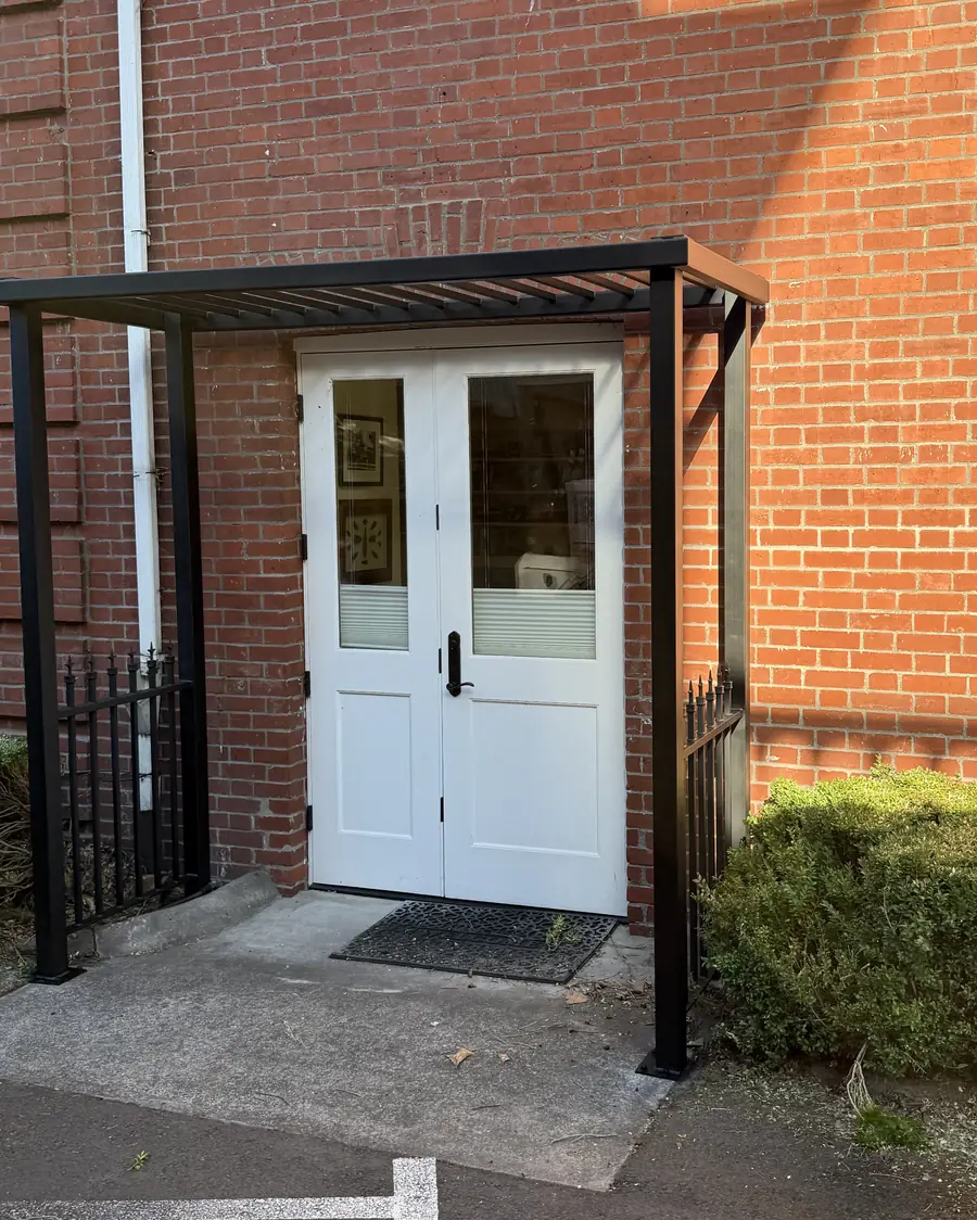 Black steel canopy over the same double doors of the brick building