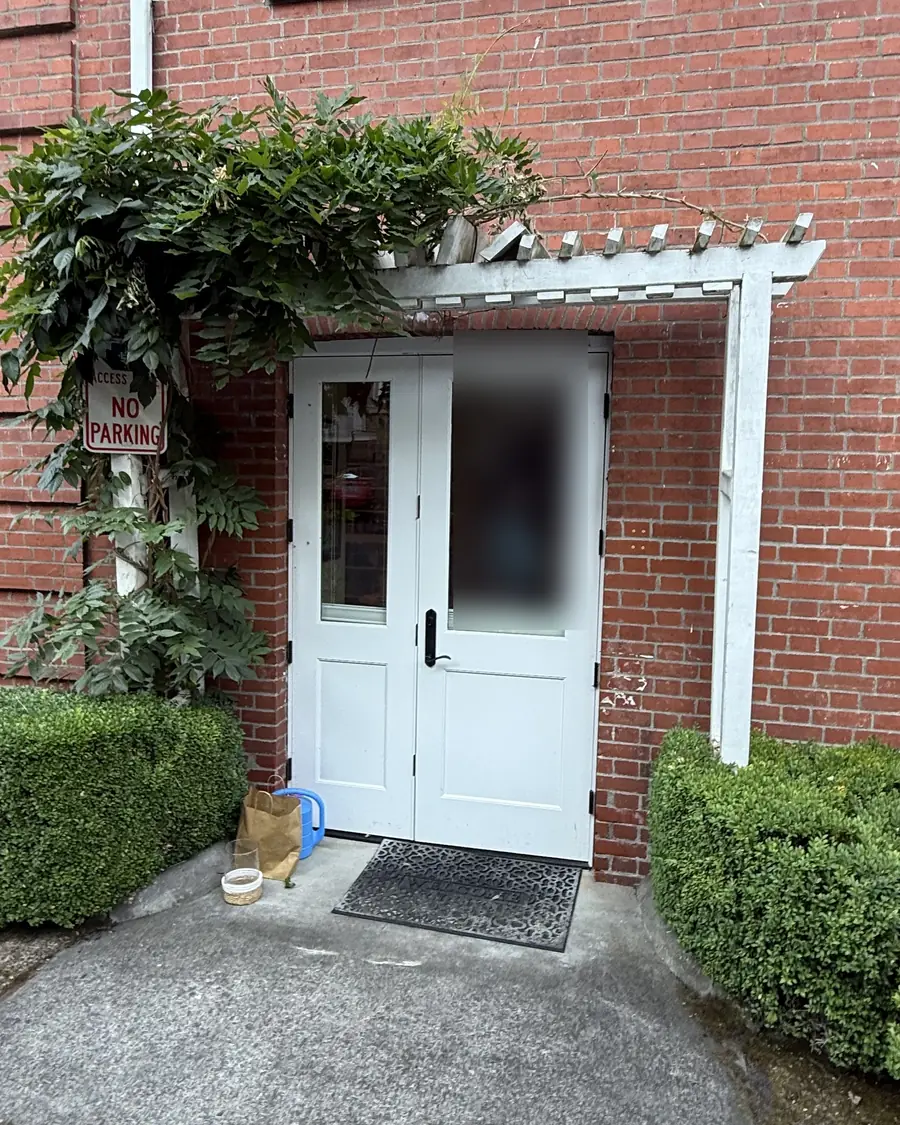 Old white wood trellis over the double doors of a brick building