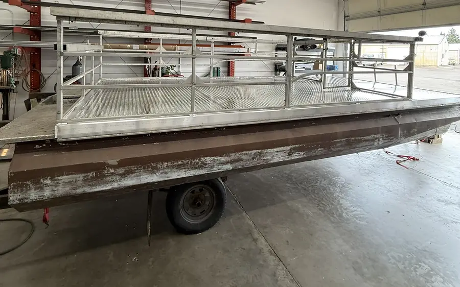 Pontoon boat on a trailer in the shop with a new aluminum diamond-plate deck